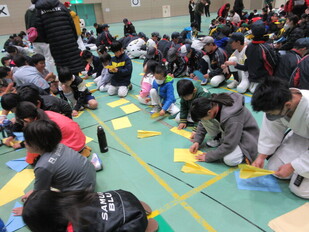 子どもたちが紙飛行機を折っている写真