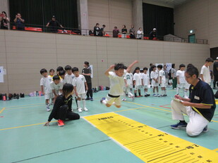 団員が立幅跳びをしている写真