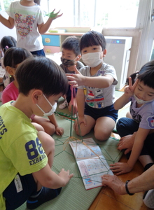 写真:あやとりで東京タワーを作る年長さん