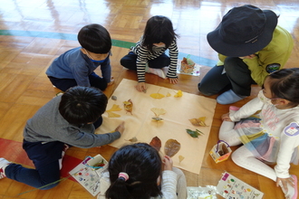 写真：グループで相談しながら葉っぱを並べる年長さん