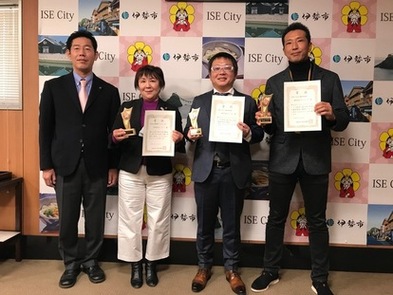 市長が左端に立ち、隣に表彰者が賞状を胸元に掲げて4人並んでいる写真