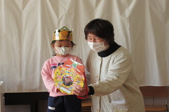 写真:園長先生にプレゼントをもらっている年少さん