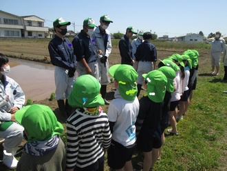 田んぼで高校生と自己紹介をする園児の写真