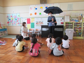 傘や長靴の話を聞く園児の写真