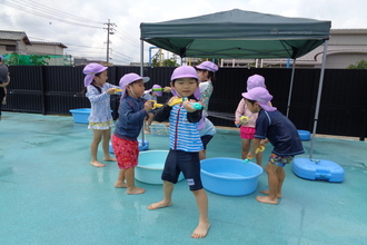 写真：プールで水遊びをする年長さん