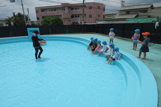 写真：大きなプールで水遊びをする子ども達