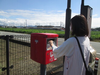 手紙をポストに投函する職員の写真