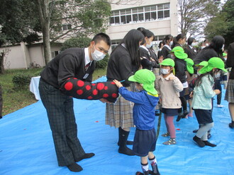 高校生の人形を見せてもらう園児の写真