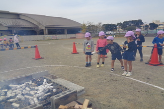 写真：火の中に芋を投げ入れる年長児