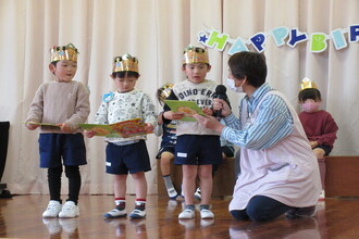 写真：園長先生よりカードを受け取る子ども達