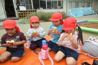 写真：園庭でお昼ご飯を食べる子ども達