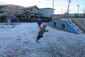 写真：雪の積もった中で遊ぶ年長児