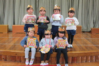 写真：金の冠と誕生カードを持つ1月生まれのお友達7人