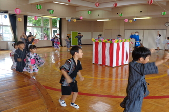 盆踊りを輪になって踊っている年長児