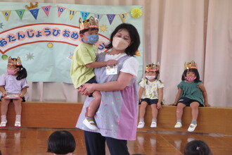 園長に抱っこのプレゼントをしてもらい喜ぶ年中組の男児