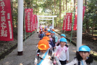 手をつないで官舎神社の鳥居を歩く年中組の子ども達