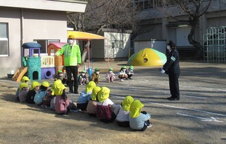 園庭で婦警さんから、道路の歩き方や横断の仕方について話を聞いています