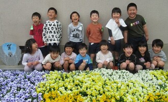 5歳児　みどり組の子どもたち花壇の前で集合写真