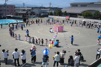 園庭で盆踊りを踊っている園児と観覧している保護者