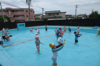 プールで水遊びをする年中児