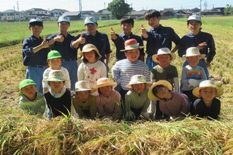 収穫した稲の山と高校生と集合写真