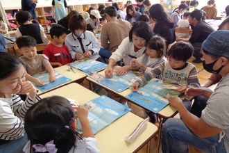おうちの人と月刊誌に取り組む年長児