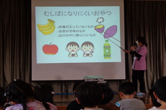 スライドを見て虫歯になりにくいおやつの説明を受ける年中児