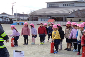 水消火器を使って消火体験をする年長児