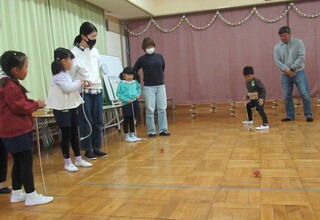 こま回しにチャレンジするみどり組をおうちの人たちが見守っています