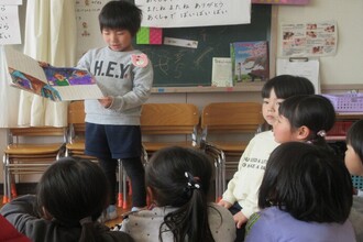 手作り絵本を読み着せている年長児