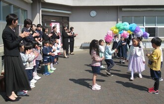 園庭で在園児がアーチを持ってお見送り