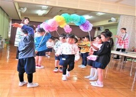 新入園児が在園児が持っているアーチをくぐっているところ