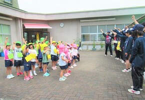 子どもたちと高校生が全員でエイエイオーをしているところ