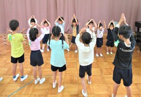 3歳児が4歳児と5歳児の前で体操の手本をしているところ