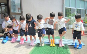 3歳児が立って長靴を履いているところ