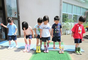 4歳児が立って長靴をはいているところ