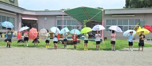 4歳児が園庭で傘をさしているところ