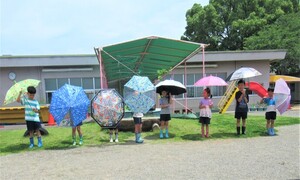 5歳児が園庭で傘をさしているところ