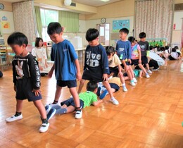 5歳児が足でトンネルをして3歳児と4歳児がトンネルをくぐっているところ