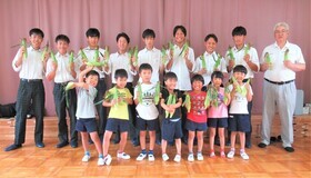 5歳児がとうもろこしをもって高校生と集合写真