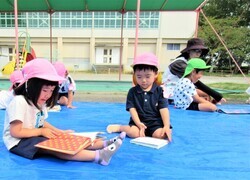 年少組がシートに座って絵本を読んでいるところ