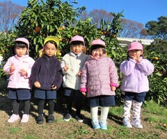 3歳児がみかんを持ってポーズをしているところ