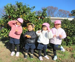 3歳児がみかんを持ってポーズをきめているところ