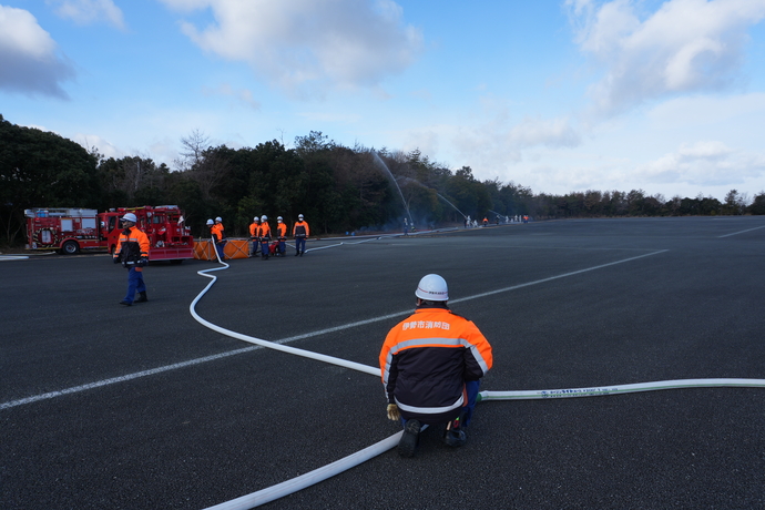 分岐したホースから放水箇所を見る団員の写真