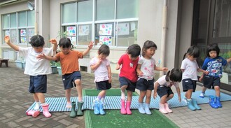3歳児が立って長靴を履いているところ