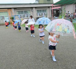 3歳児が傘を差して歩いているところ