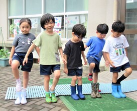 5歳児が立って長靴を履いているところ