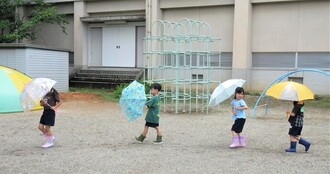 5歳児が傘を差して歩いているところ