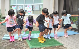 4歳児が立って長靴を履いているところ