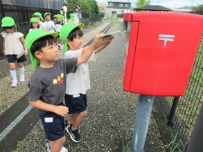 嬉しそうに紙を投函する5歳児
